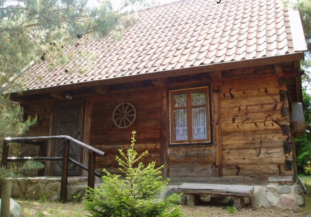 eine Blockhütte mit einer Veranda und einem Fenster in der Unterkunft Mazurska Chatka in Zyzdrojowy Piecek
