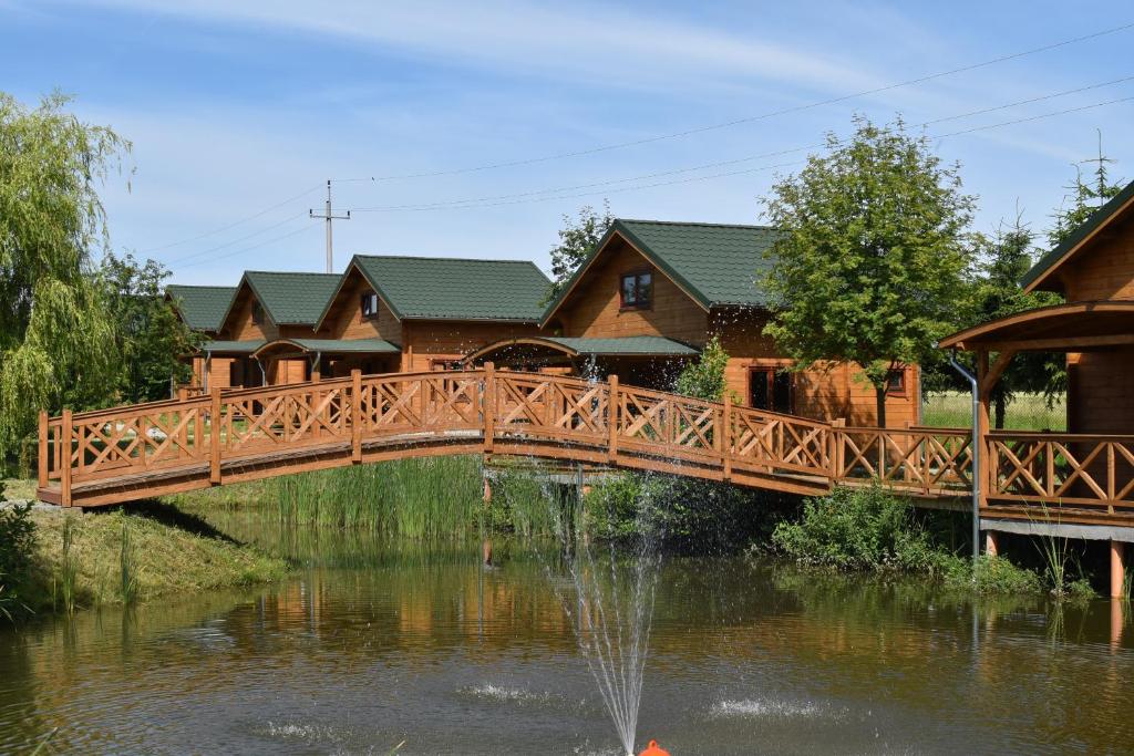ギジツコにあるOrion Domki Letniskoweの家の前の池に架かる木橋
