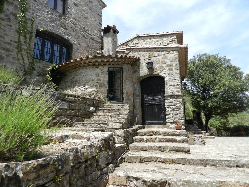 una vieja casa de piedra con escaleras que conducen a una puerta en Chambre Cévennes: Piscine, lamas, rivière, en Cros