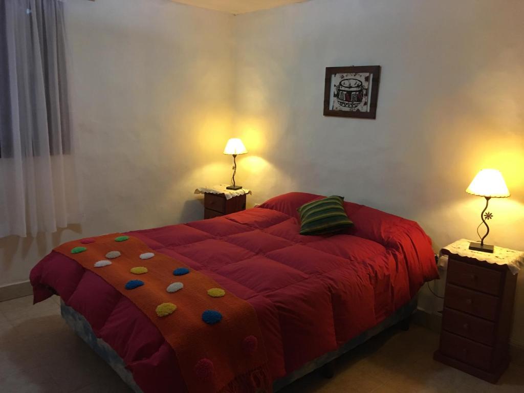 a bedroom with a large red bed with two lamps at Cabañas Ernes Huasi in Tafí del Valle