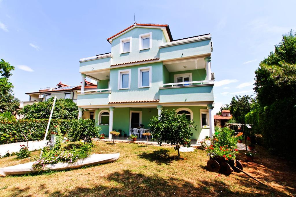 a blue house with trees in a yard at Studios Simona in Medulin