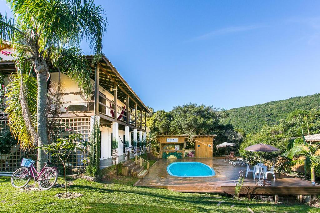a house with a deck and a swimming pool at Pousada Guarda Beach House in Guarda do Embaú