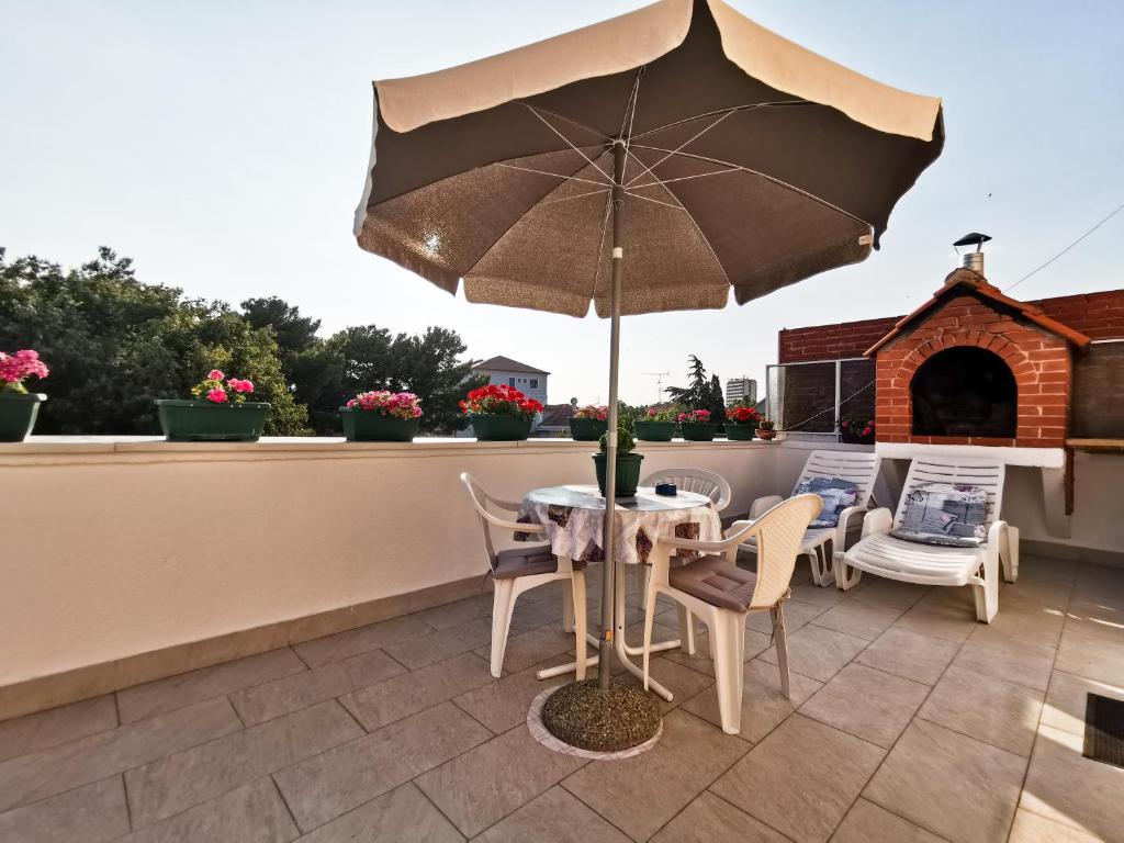 a table and chairs with an umbrella on a patio at Da Vinko Beach Apartments in Split
