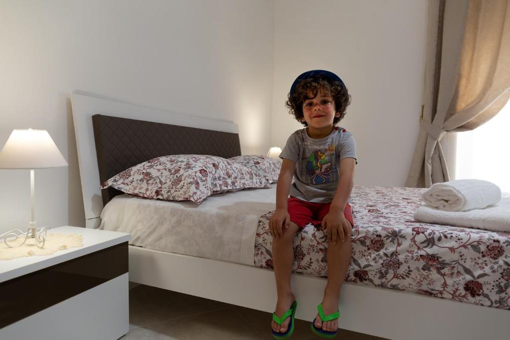 un jeune garçon assis sur un lit dans une chambre dans l'établissement La Casa di Ninetta Amalfi Coast, à Vietri
