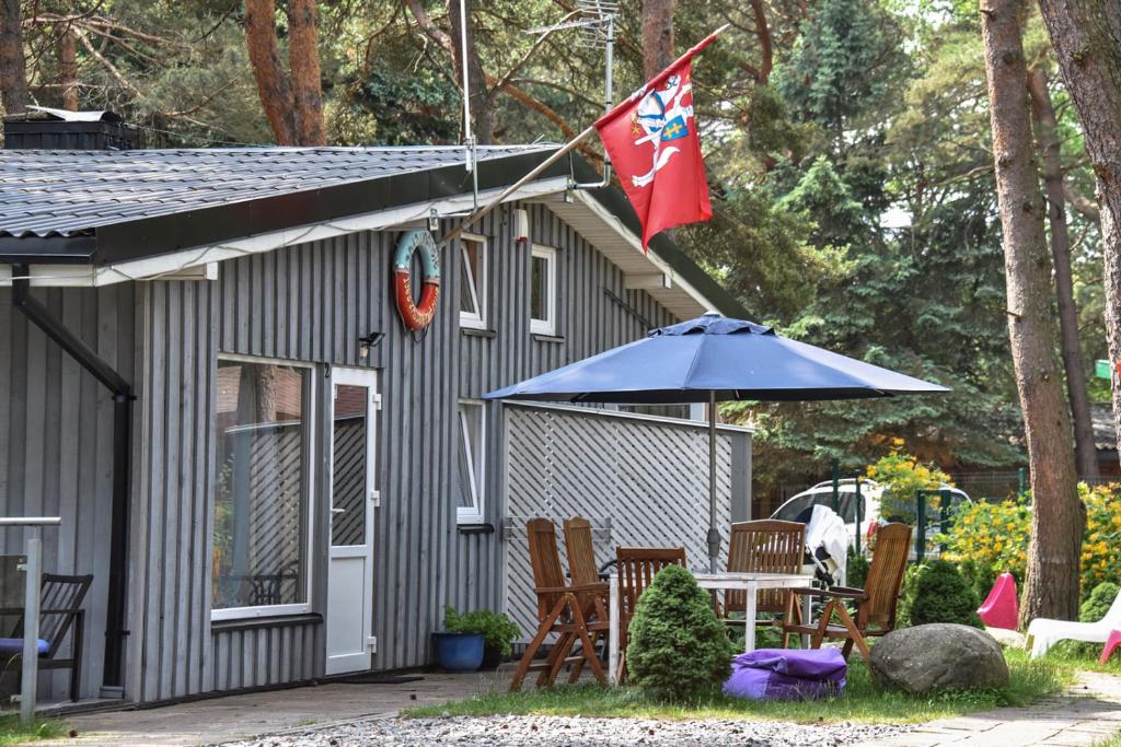 une maison avec un drapeau, une table et un parasol dans l'établissement Undinėlė, à Šventoji