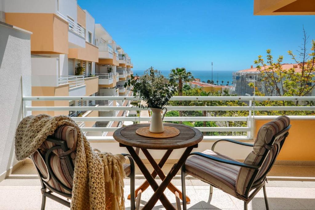 a table and chairs on a balcony with a view of the ocean at Fantastic Seaside Family Apartment with Pool in Parede