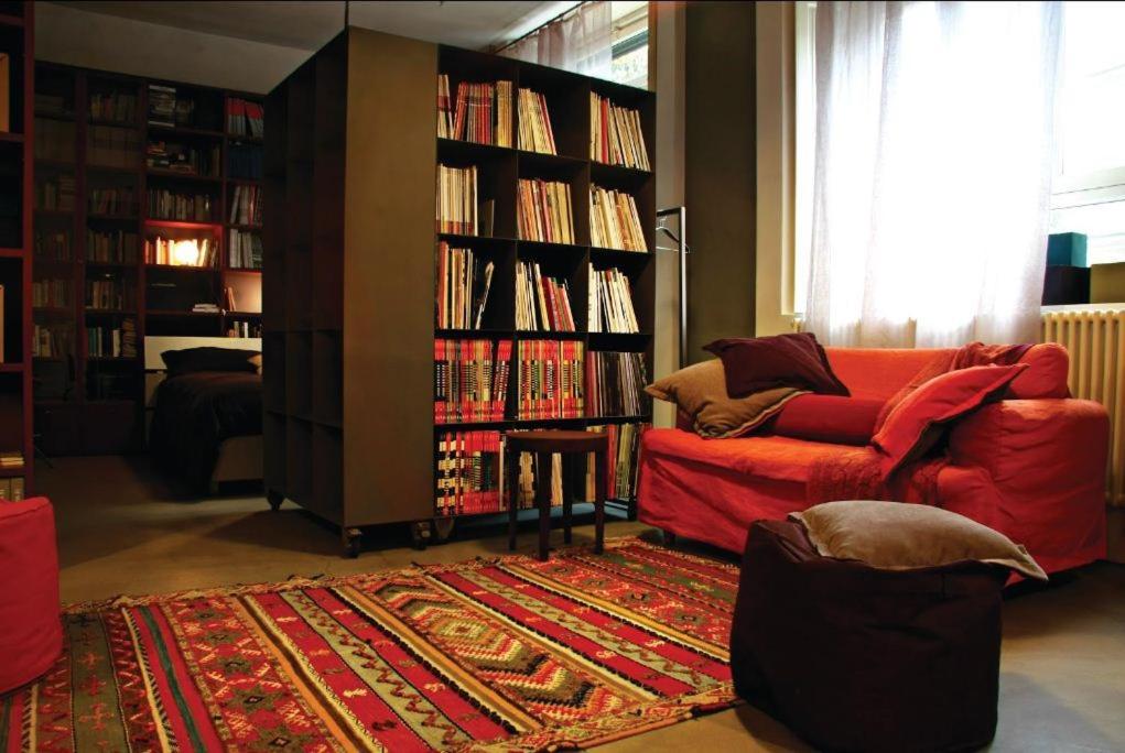 uma sala de estar com um sofá vermelho e prateleiras de livros cheias de livros em I Mulini B&B em Vigevano