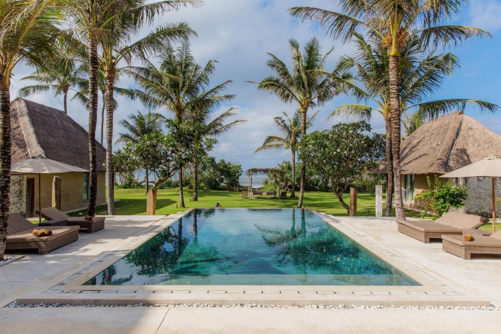 una piscina con palmeras y un complejo en Beraban Beach House en Tabanan