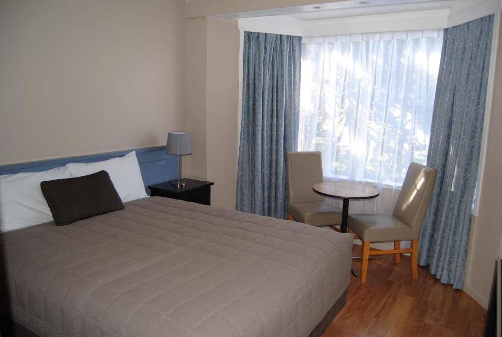 1 dormitorio con cama, mesa y ventana en Airlie House Motor Inn, en Scone