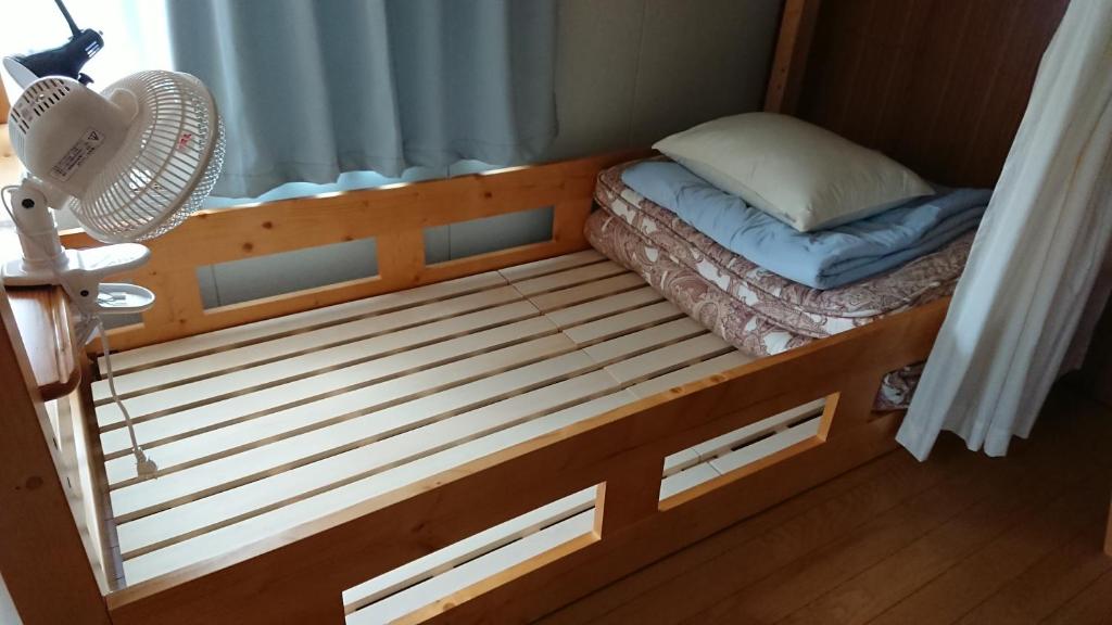 uma pequena cama num quarto com uma ventoinha em Guest house Minna no Ie em Achi