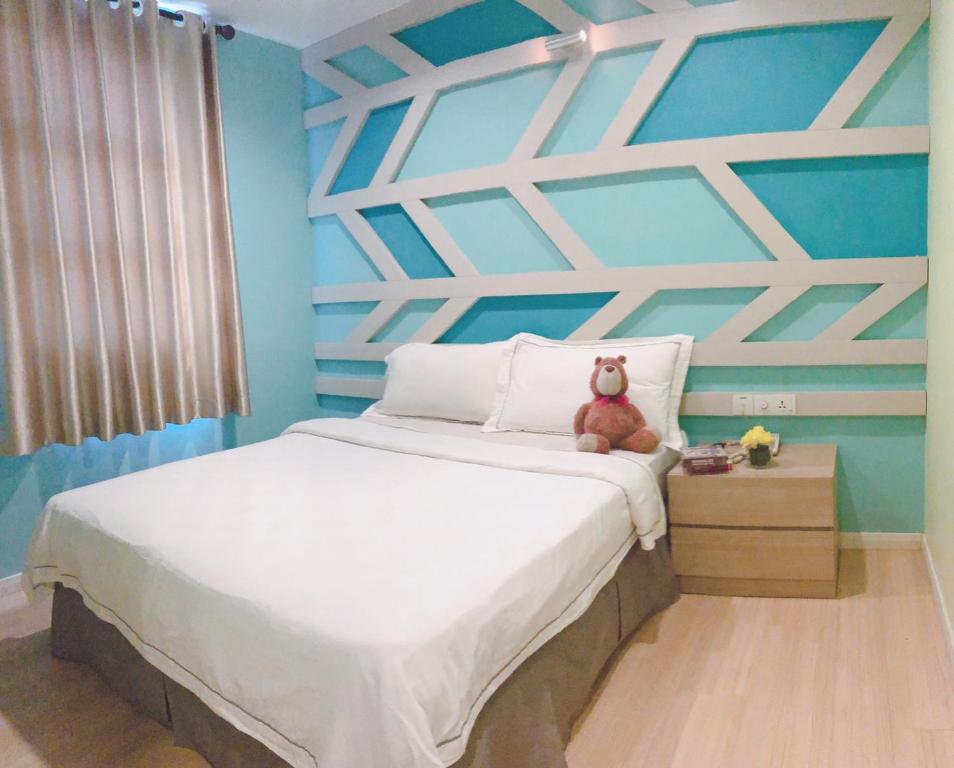 un osito de peluche sentado en una cama en un dormitorio en Sunshine Inn en Melaka