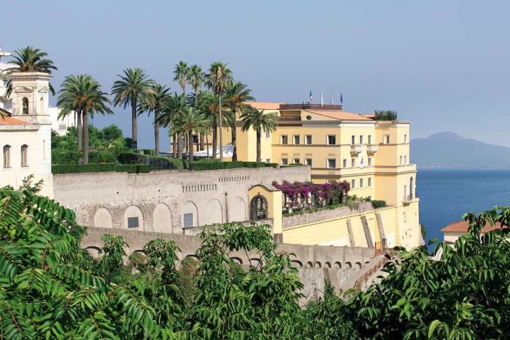 un grupo de edificios con palmeras y el océano en Grand Hotel Angiolieri, en Vico Equense