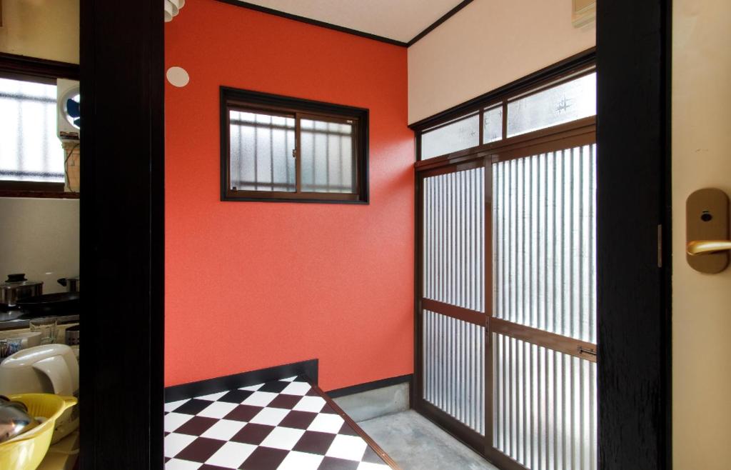 um quarto com uma parede laranja e uma porta de correr em Hakko Ichiu em Osaka