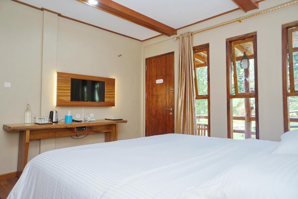 een slaapkamer met een wit bed en een televisie bij Spring Hill Hotel Ruteng in Ruteng