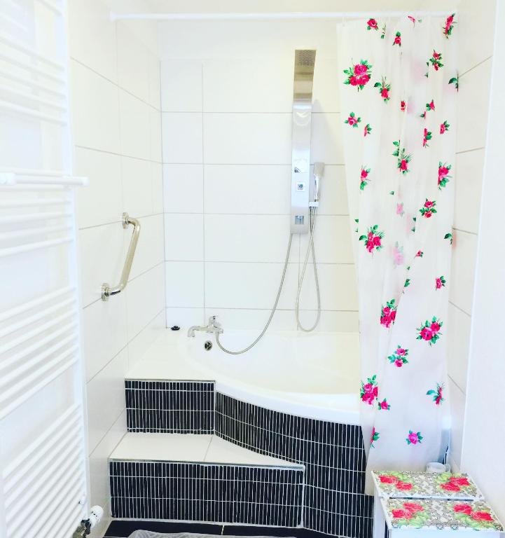 a bathroom with a tub and a shower curtain with flowers at Bed and Breakfast 57 in Asuel
