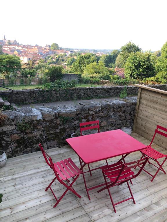 une table rose et quatre chaises sur une terrasse en bois dans l'établissement Gîte proche du Puy du Fou, à Mortagne-sur-Sèvre