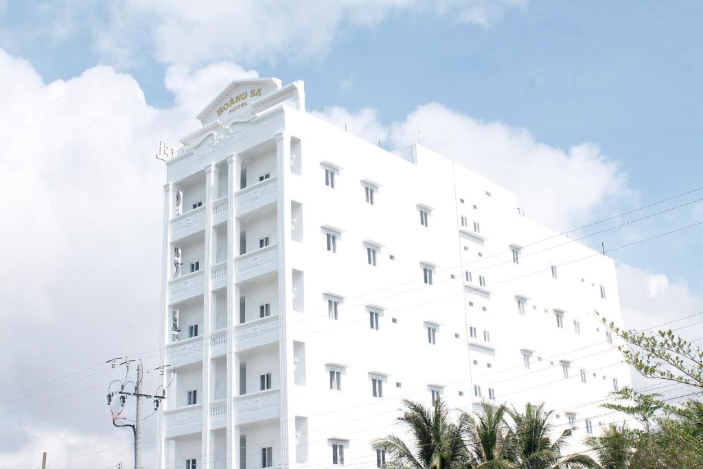 a white building with palm trees in front of it at Hoàng Sa Hotel in Xóm Nhà Mát