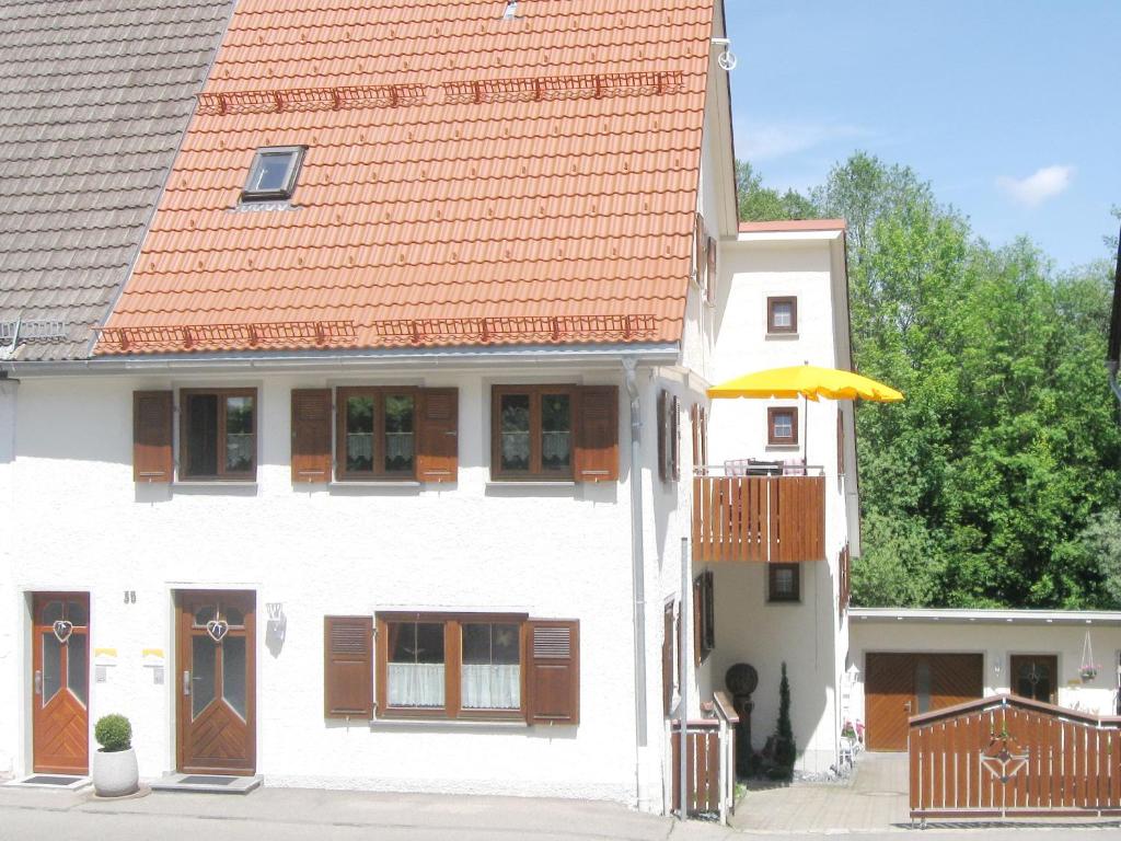 uma casa branca com um telhado laranja e um guarda-chuva em Ferienwohnung Wagner em Isny im Allgäu