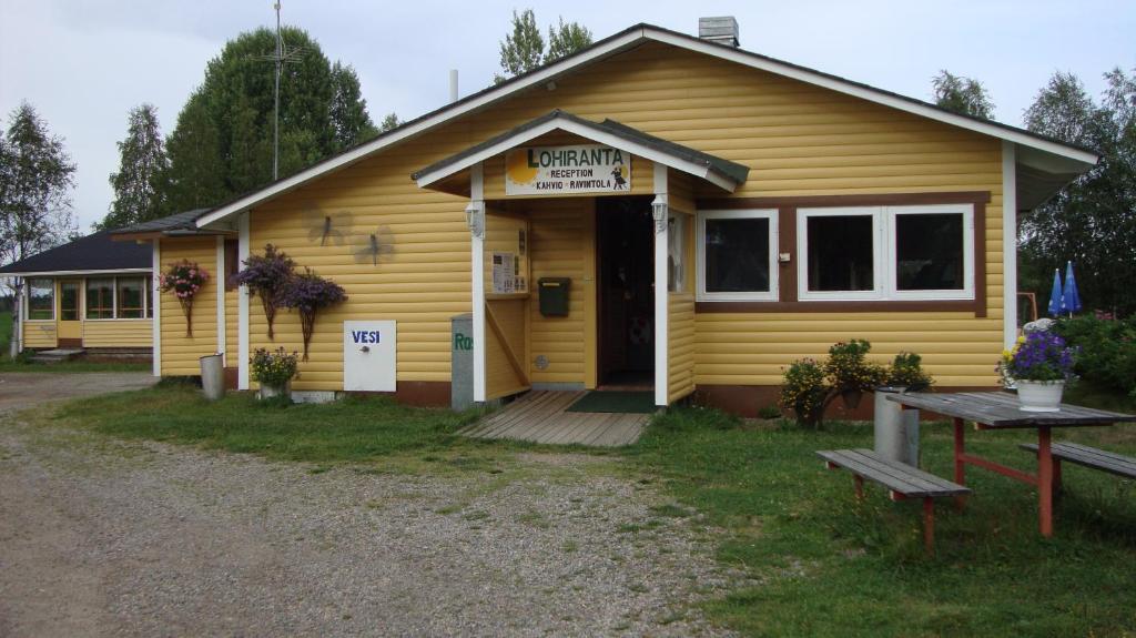 un pequeño edificio amarillo con un cartel en él en Lohirannan lomakylä, en Sukeva