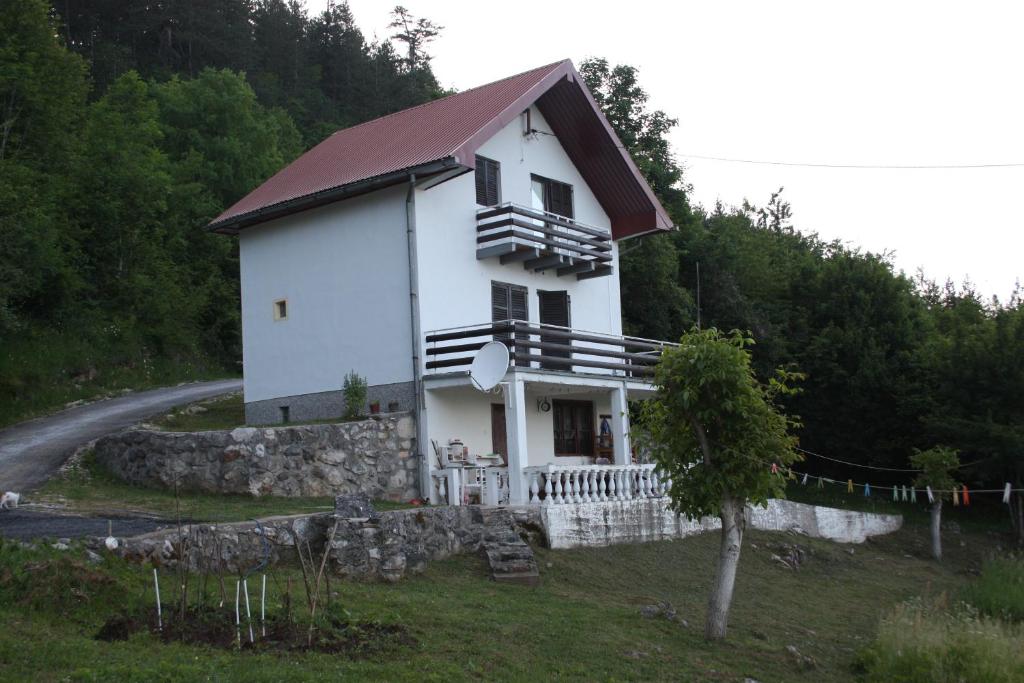 a white house on top of a hill at Apartmani Rocen in Žabljak