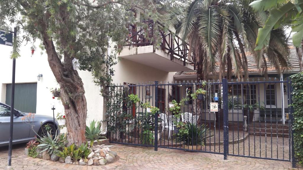 a wrought iron fence in front of a house with a tree at MAVILLA STELLENBOSCH B&B in Stellenbosch