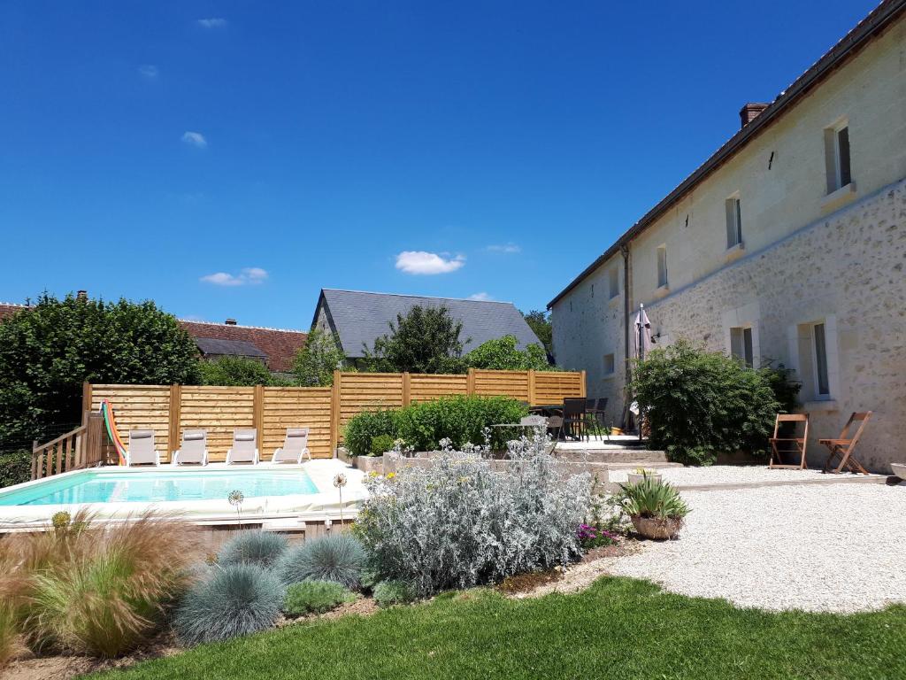 a swimming pool in a yard next to a building at L'Ayguevives in Faverolles-sur-Cher