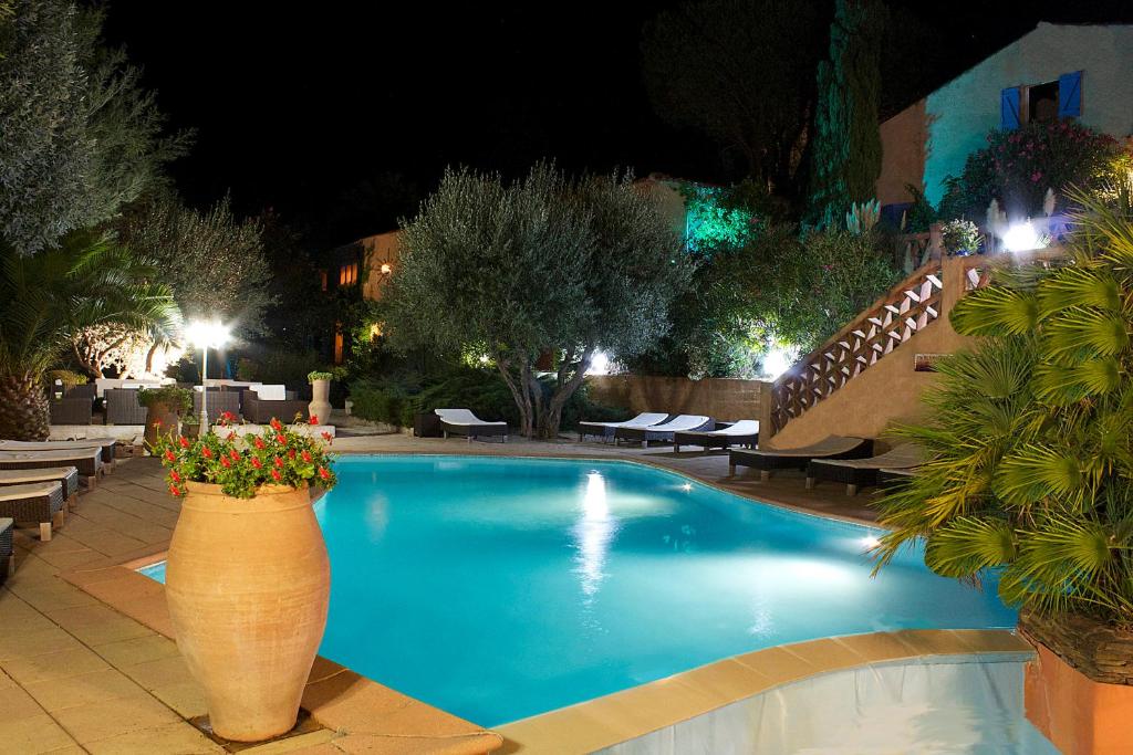 una piscina por la noche con un jarrón grande con flores en Athénopolis, en Grimaud