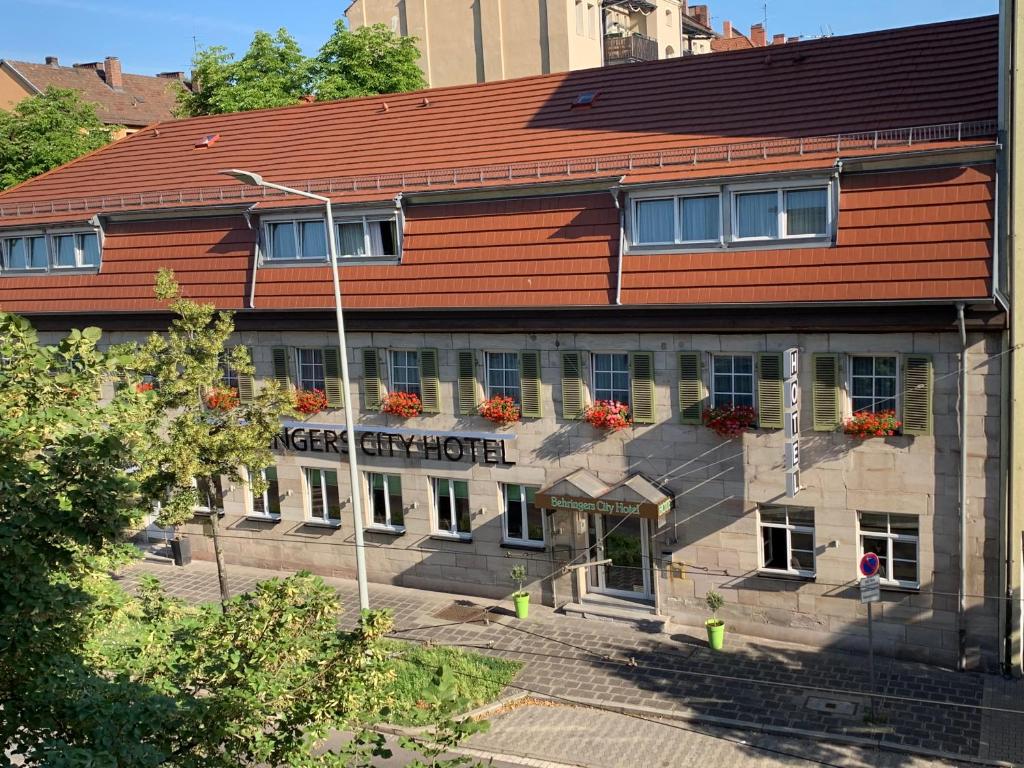un edificio con tetto rosso e fiori alle finestre di Behringers City Hotel Nürnberg a Norimberga