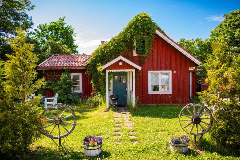 uma casa vermelha com duas rodas de carroça à frente. em Westergårds em Föglö