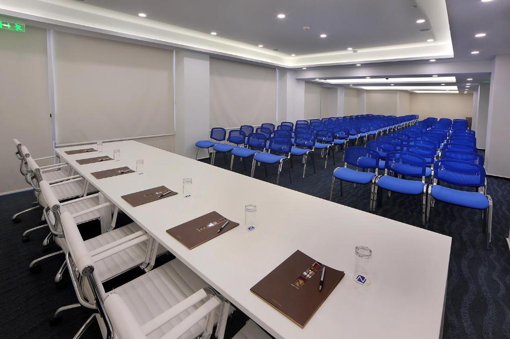 a conference room with white tables and blue chairs at Nestor Hotel in Ayia Napa