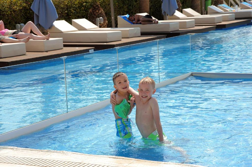 two children are standing in a swimming pool at Nestor Hotel in Ayia Napa