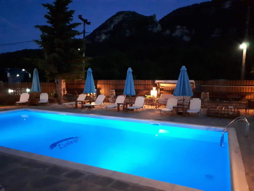 a swimming pool with chairs and umbrellas at night at Ziakas Rooms in Zákas