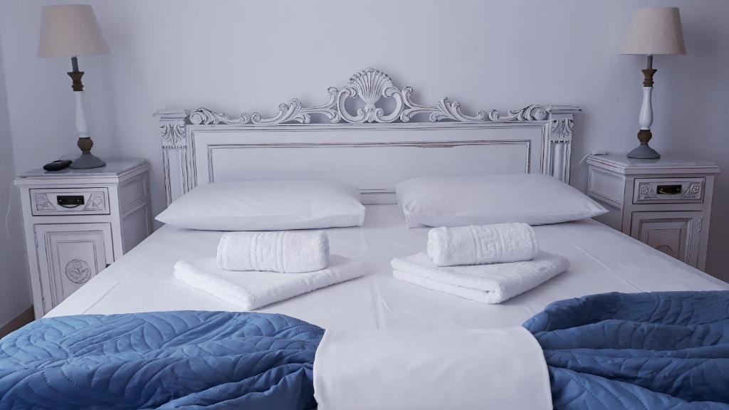 a white bedroom with a bed with two pillows at Christos Rooms in Palaiochóra