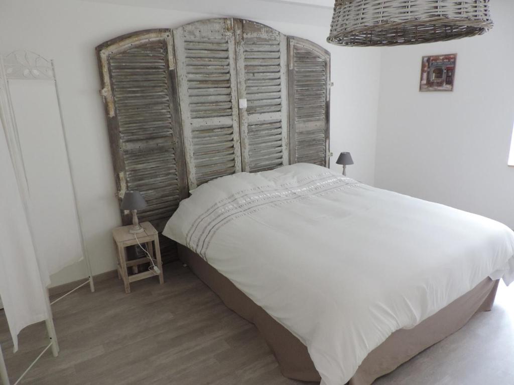 a bedroom with a large bed with a wooden headboard at La Maison d’Elise in Beine