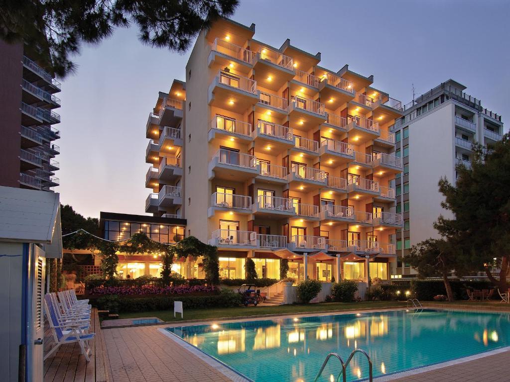 a hotel with a swimming pool in front of a building at Hotel Atlantic in Lignano Sabbiadoro