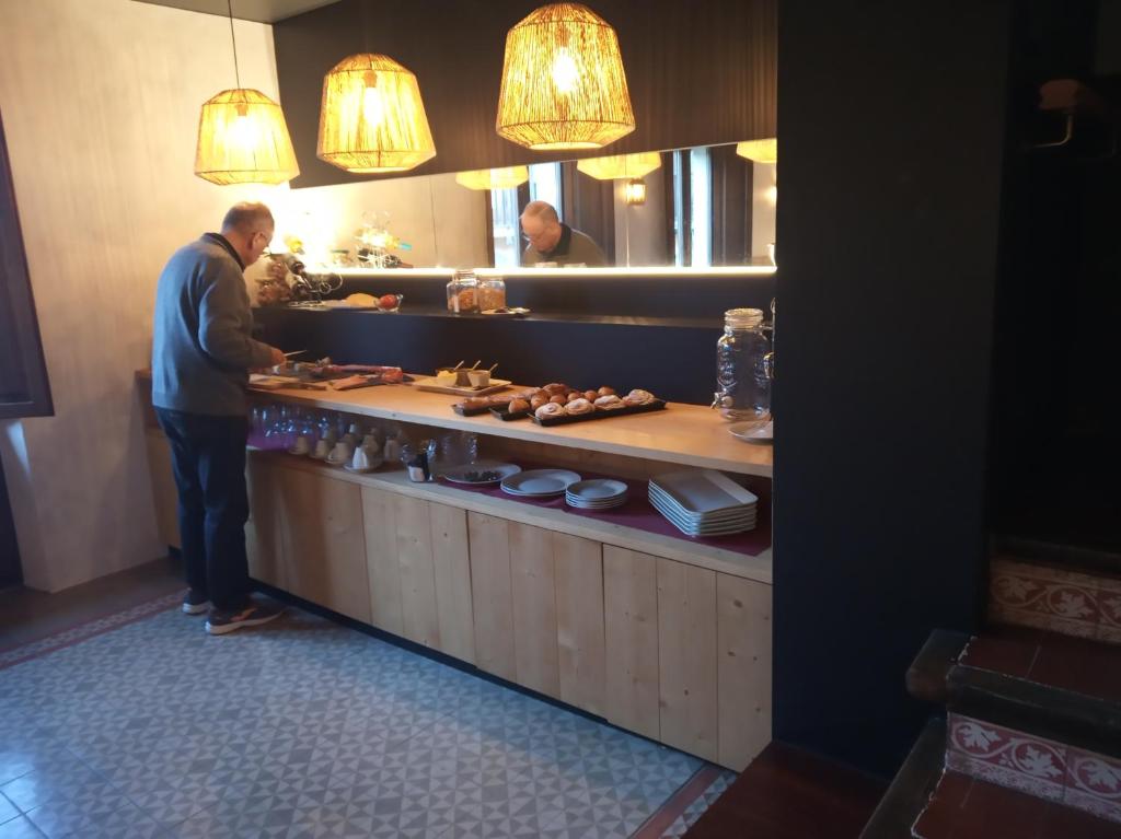 a man standing at a buffet in a restaurant at CAN MENCIÓ - Plaça Major in Santa Pau