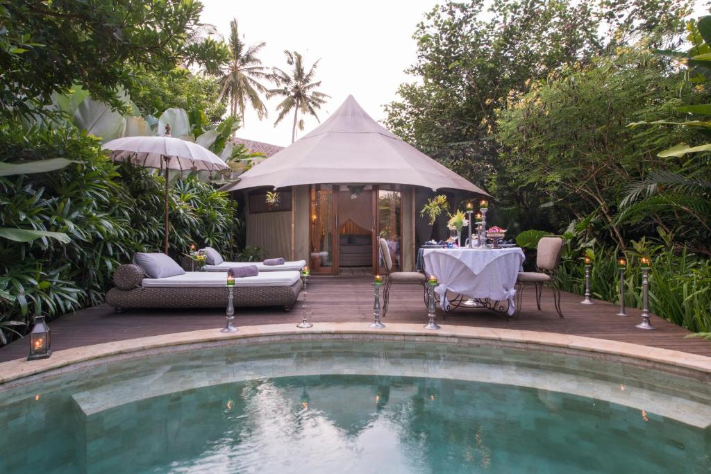 a swimming pool with a table and a tent at Sandat Glamping Tents in Ubud