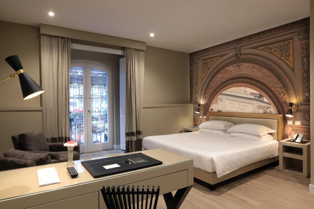 Pokój hotelowy z łóżkiem i biurkiem z biurkiem w obiekcie Caruso Place Boutique & Wellness Suites w mieście Neapol