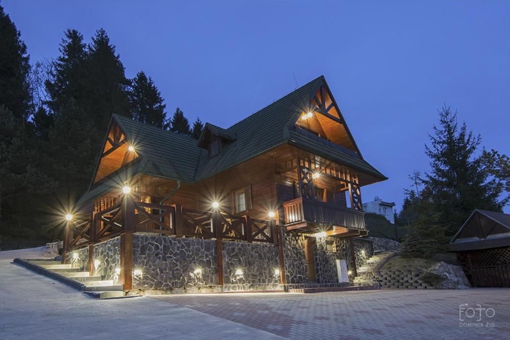 a large wooden house with lights on it at night at Chata Studnička in Litmanová