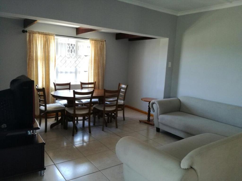 sala de estar con sofá, mesa y sillas en The Crescent Guesthouse on Waterfall, en Durban