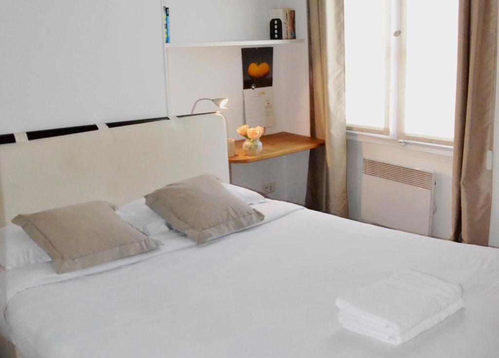 a white bed with two pillows in a bedroom at Latin Quarter - Saint Michel Unit 004 in Paris