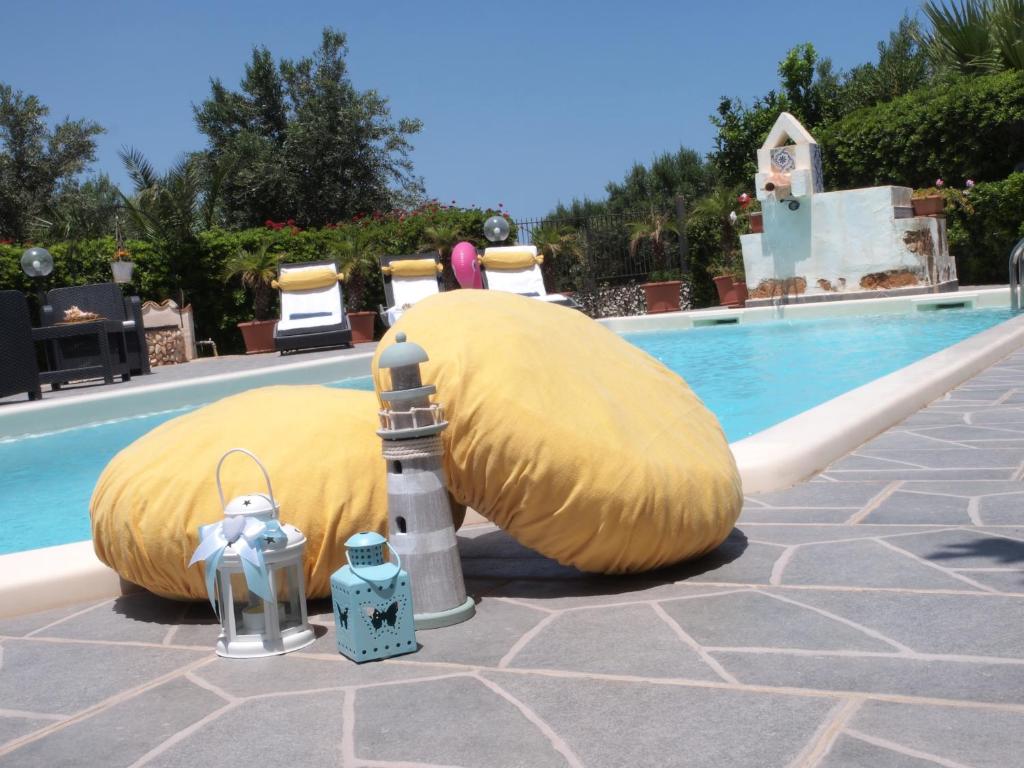 un grand fauteuil à poufs jaune à côté de la piscine dans l'établissement Casa Vacanza Perla Bianca, à Castelluzzo
