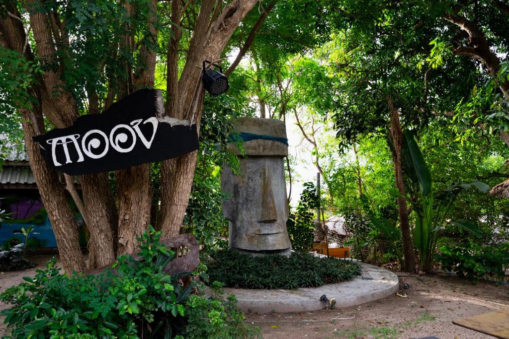 a sign hanging from a tree next to a statue at Moov Inn Garden Hostel in Ko Tao