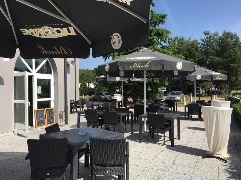 een restaurant met tafels, stoelen en parasols bij Hôtel Restaurant de L'Europort in Saint-Avold