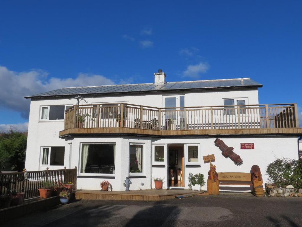 a white house with a deck on top of it at Cuil Na Sithe in Fort William