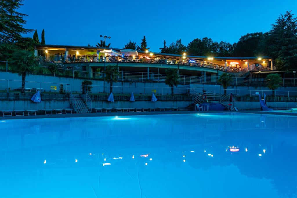 a swimming pool at night with a restaurant in the background at Camping Village Il Poggetto in Troghi