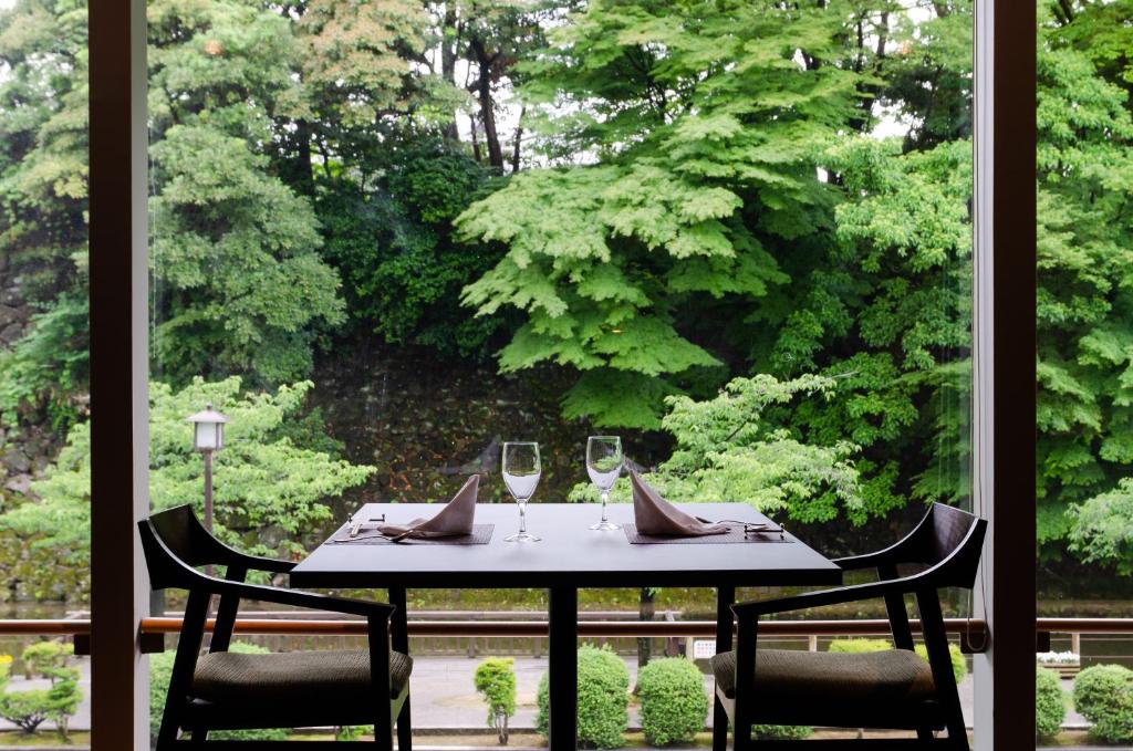 a table with two chairs and two wine glasses at KKR Hotel Kanazawa in Kanazawa