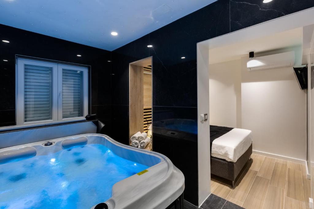 uma grande banheira azul numa sala com um quarto em Downtown Marcius Luxury Apartment with Jacuzzi & Sauna em Zadar