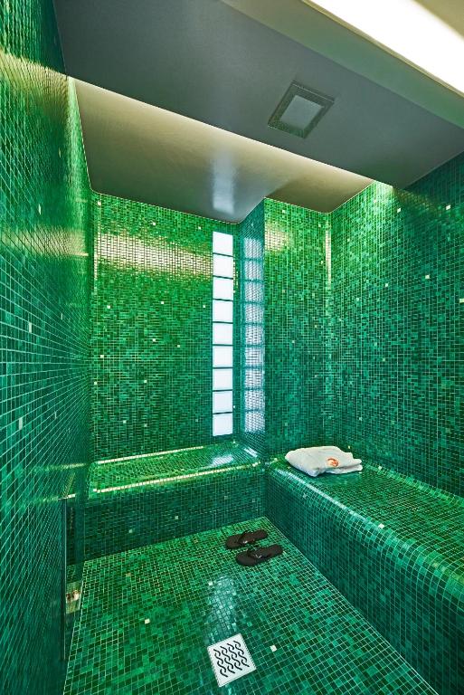 a green tiled bathroom with a tub and a window at Hotel Saturnia &amp; International in Venice