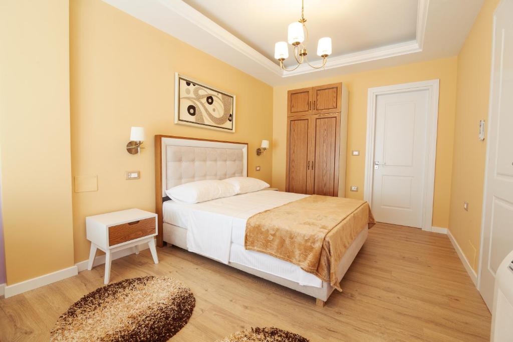 a bedroom with a white bed and a wooden floor at Eagles Philadelfia in Korçë